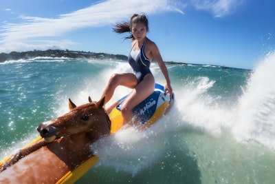【謎画像】暑さで馬が溶けて貼りついたサーフボードで波に乗る女の子